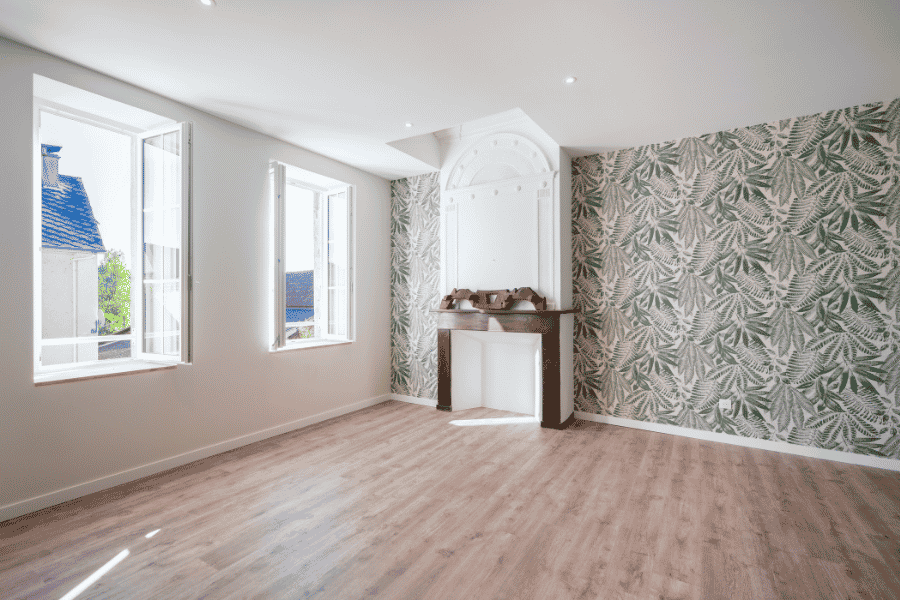 Pose de parquet flottant clair dans une pièce rénovée avec papier peint végétal à Monein – Tuheil Établissement